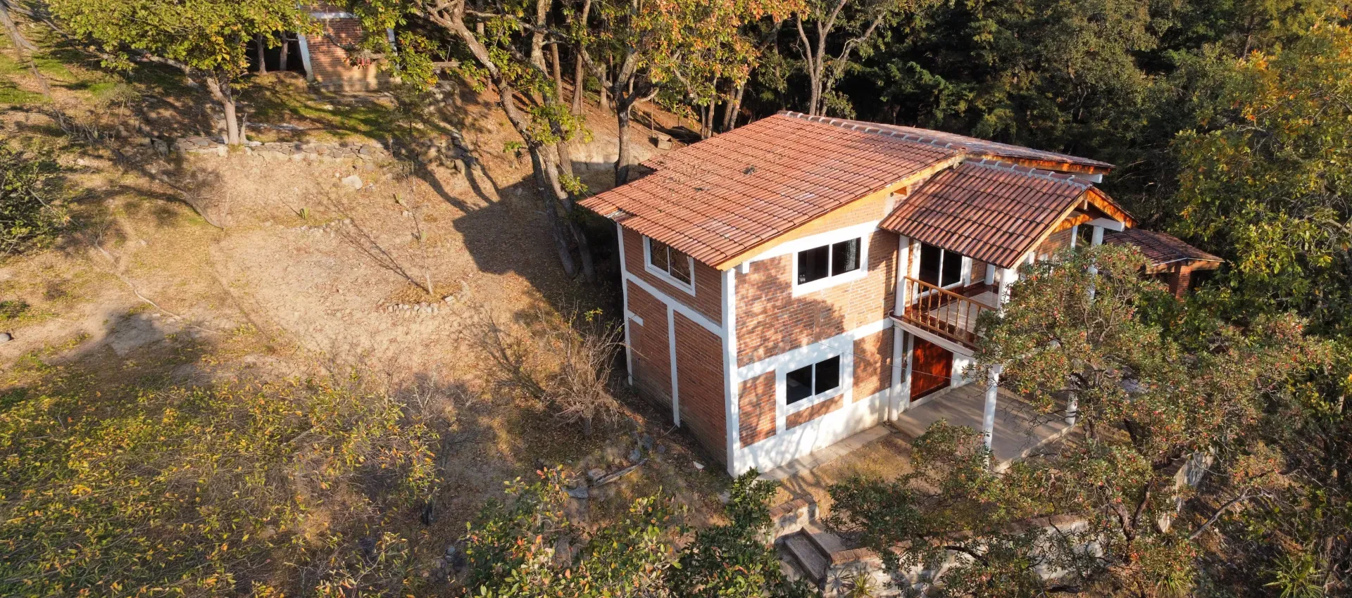 Vista aérea de una cabaña de dos pisos rodeada de bosque en Las Cascadas