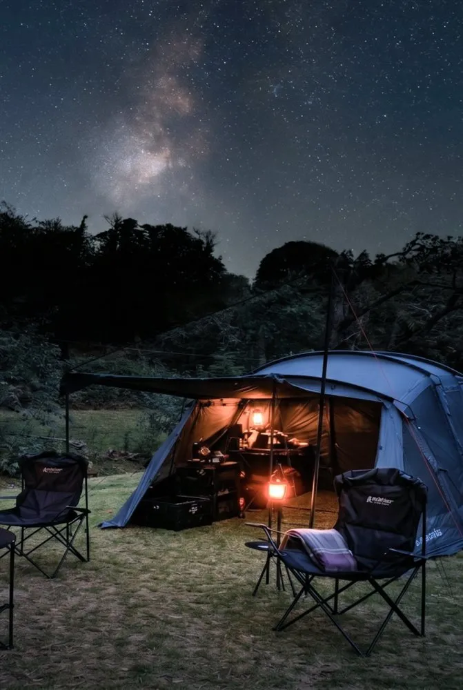 Campamento con tienda iluminada bajo un cielo estrellado