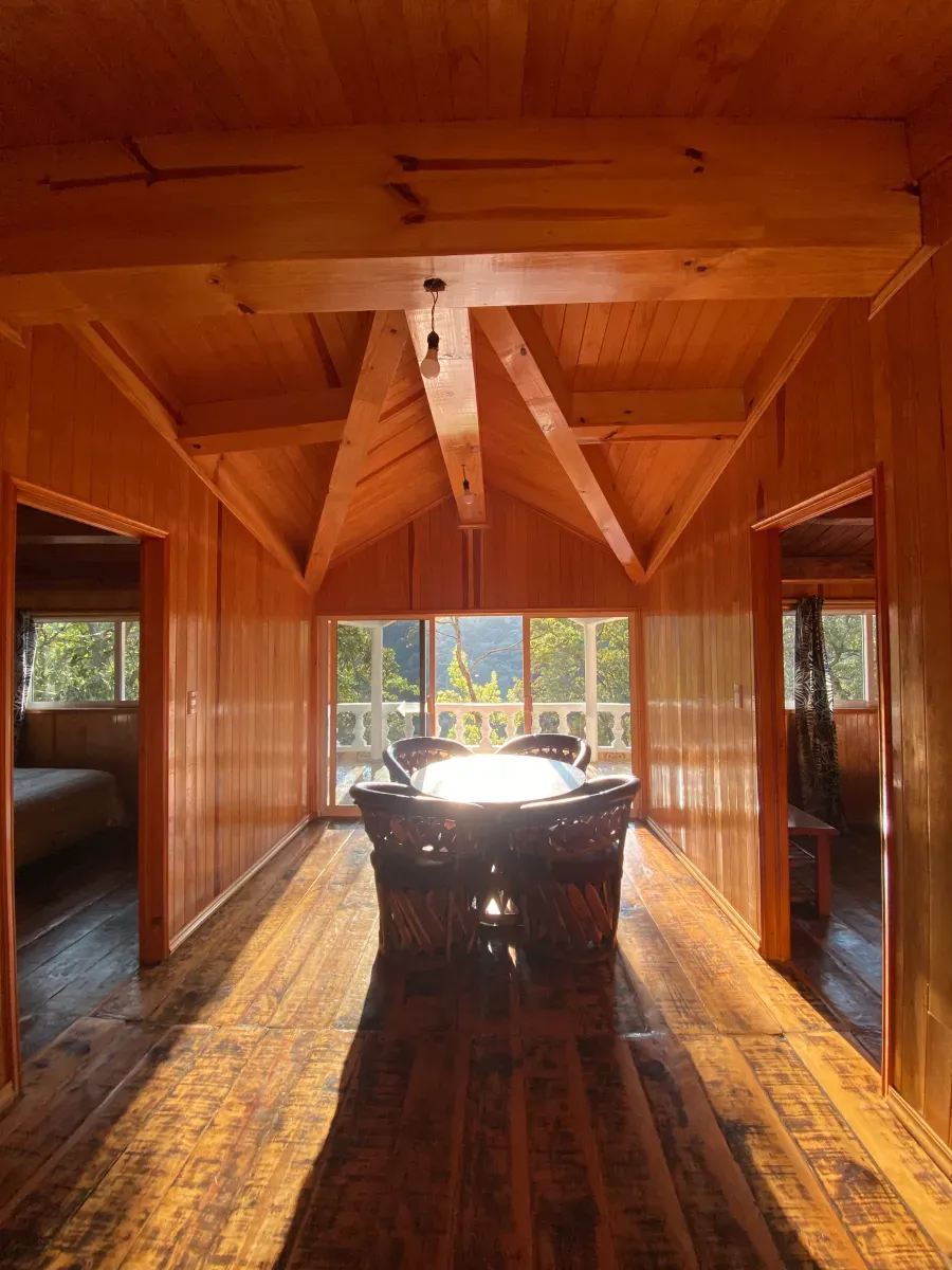 Interior de una cabaña de madera con vista al bosque en Las Cascadas